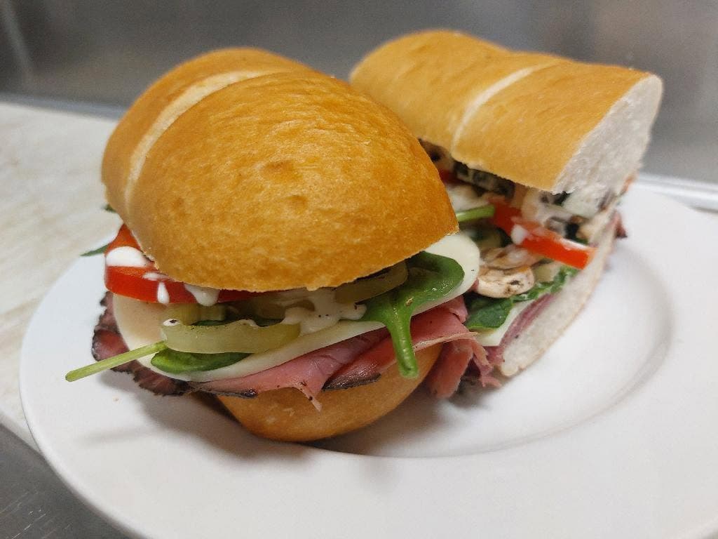 Fresh deli sandwich with roast beef, cheese, spinach, tomatoes, and mushrooms on a toasted sub roll